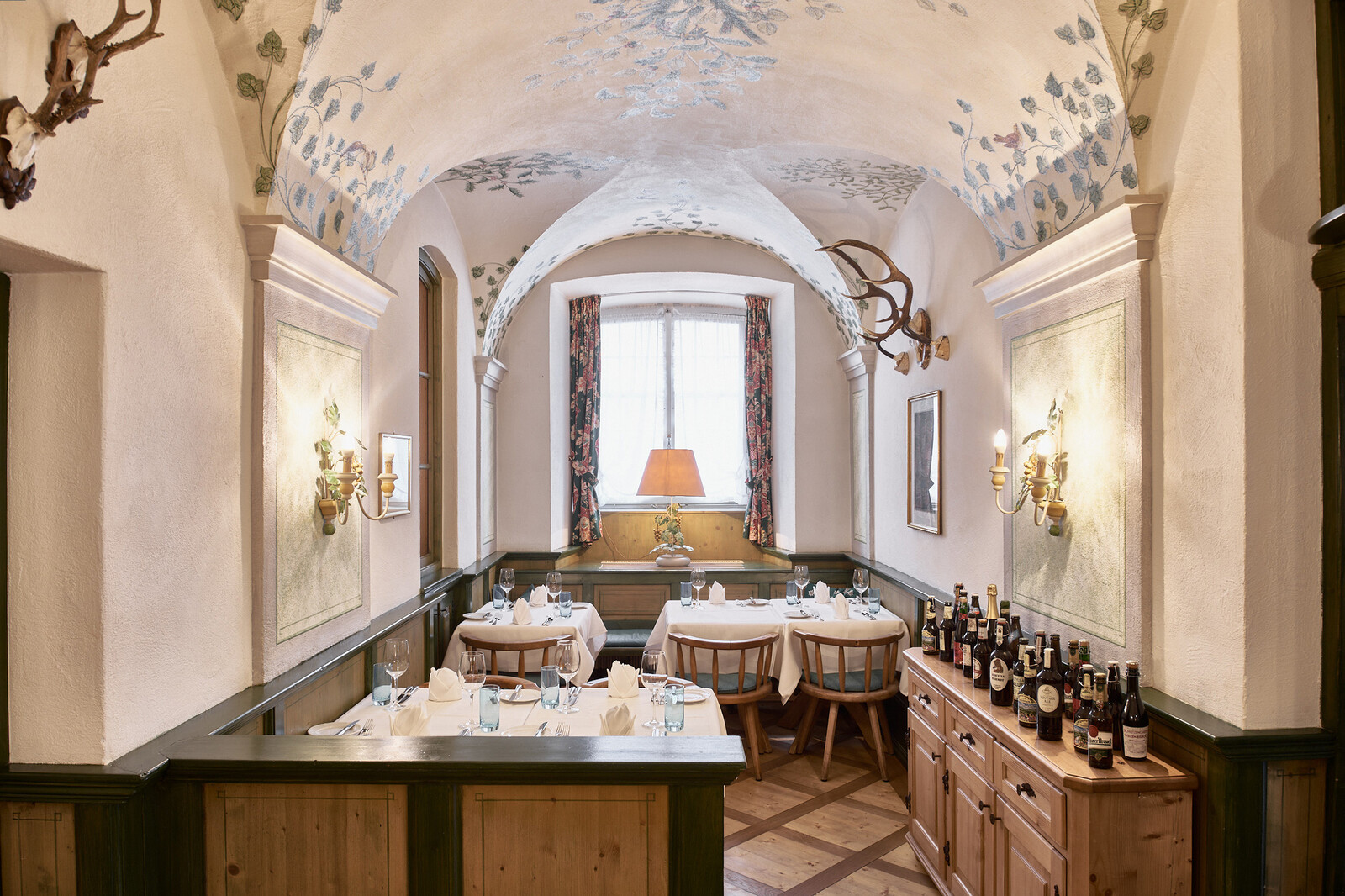 Light shines through the window at the end of the room into the Jägerstube of the Zollstube restaurant. The customs office is part of the Hotel Grand Resort Bad Ragaz, a superior luxury resort in Switzerland.