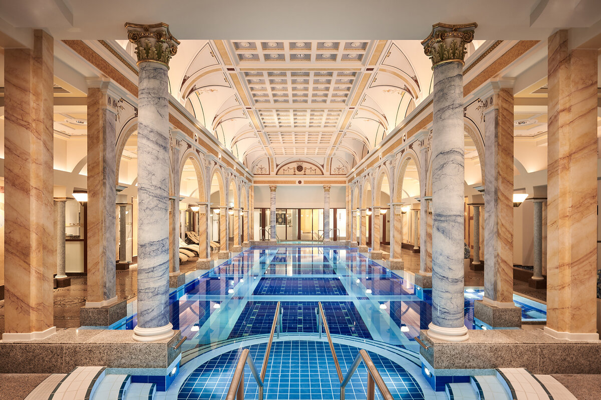 Luxurious Helenabad with blue tiles, surrounded by marble columns and arches. Elegant, serene ambiance, with soft lighting enhancing opulence.