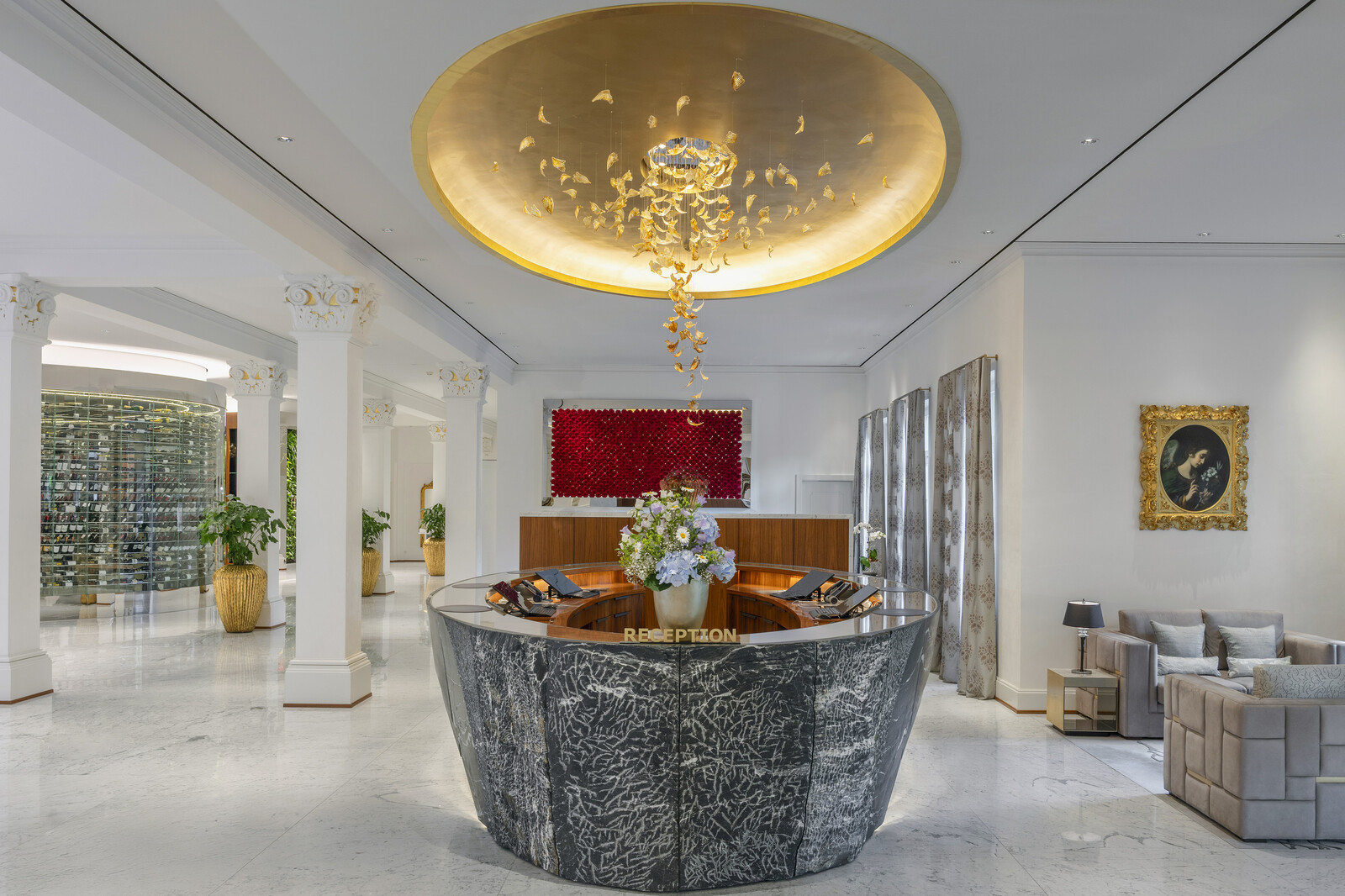 Luxurious hotel lobby of the Grand Resort Bad Ragaz with elegant marble reception desk, ornate lighting, and plush seating. Golden ceiling accents create a sophisticated ambiance.