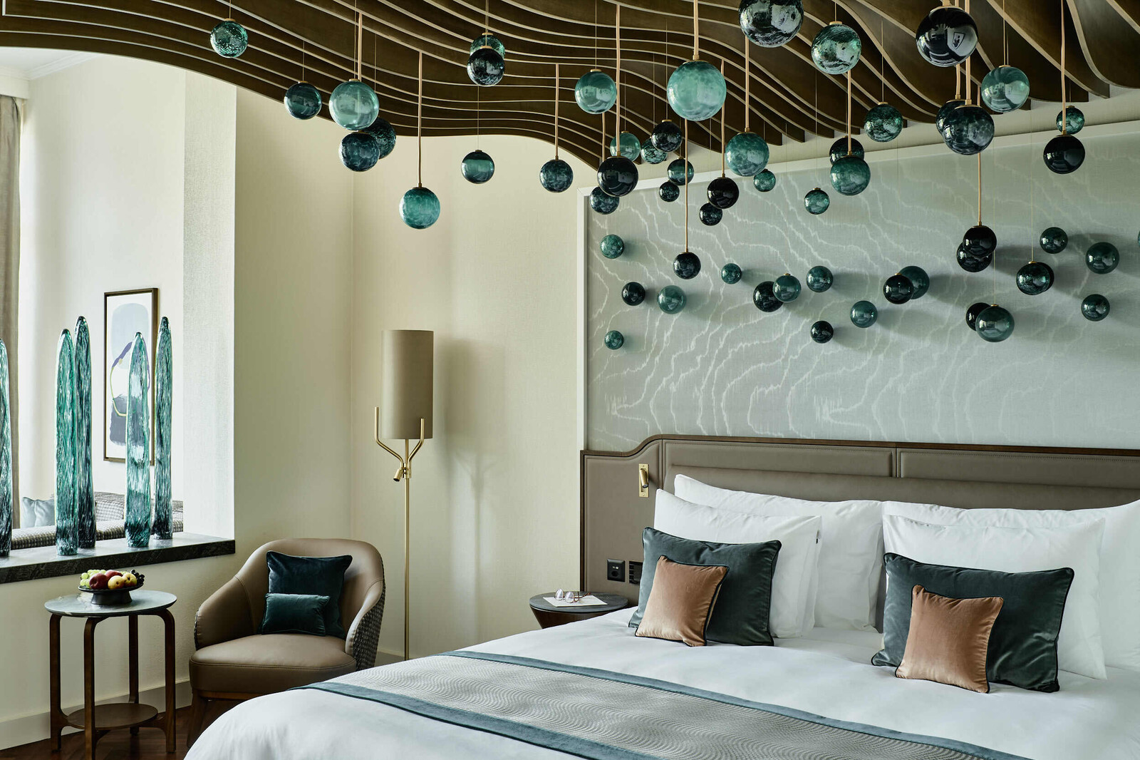 Blick auf das einzigartige Himmelbett einer Deluxe Suite im Grand Hotel Hof Ragaz. Über das Himmelbett ragen hölzerne Wellen, die mit kugelartigen blauen Lichtelementen ausgestattet sind.