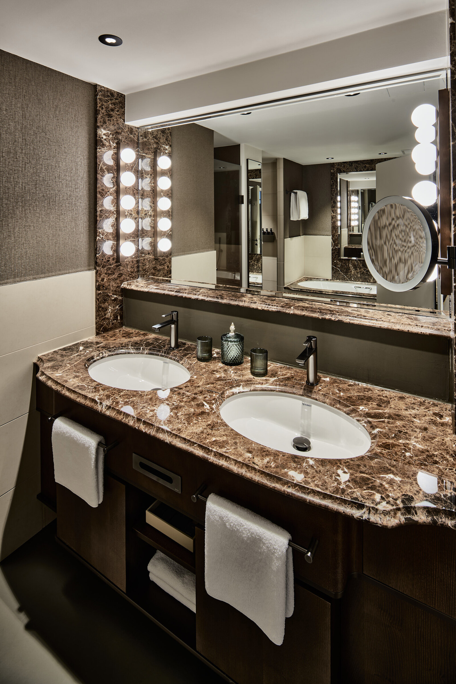 Detailed view of two marble washbasins, a mirror and light elements in a deluxe room at the Grand Hotel Hof Ragaz.