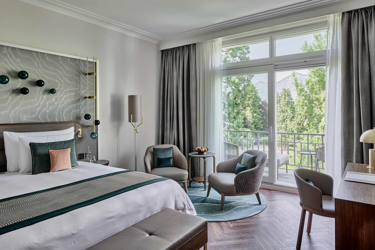 Innenansicht eines Deluxe Zimmers mit Doppelbett, kleinem Wohnbereich und Schreibtisch im Grad Hotel Hof Ragaz.