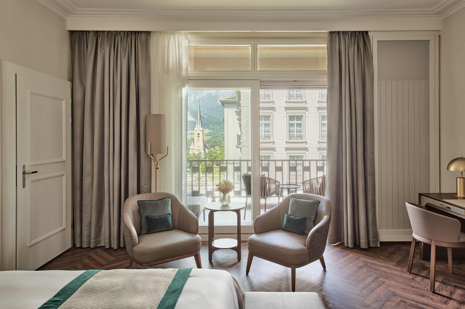 Blick vom Elternbett des Familienzimmers in Richtung der Fenster. Vor dem Fenster stehen zwei Sessel mit einem Beistelltisch.