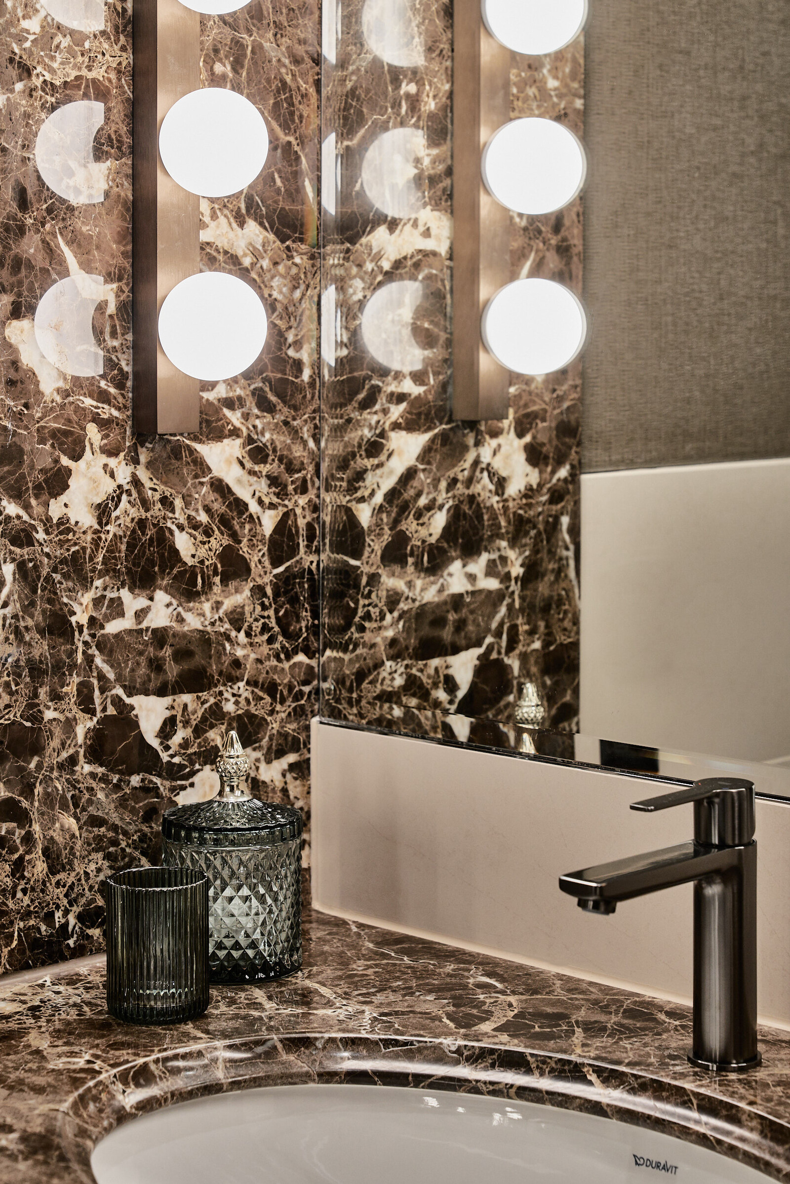 Blick auf eines der Marmorwaschbecken in einer Grand Deluxe Suite. Im Hintergrund befindet sich ein grosser Spiegel mit Licht.