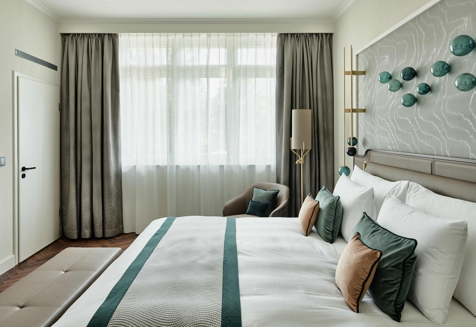 Blick auf das Bett in Richtung Fenster in einer Grand Deluxe Suite im Grand Hotel Hof Ragaz.