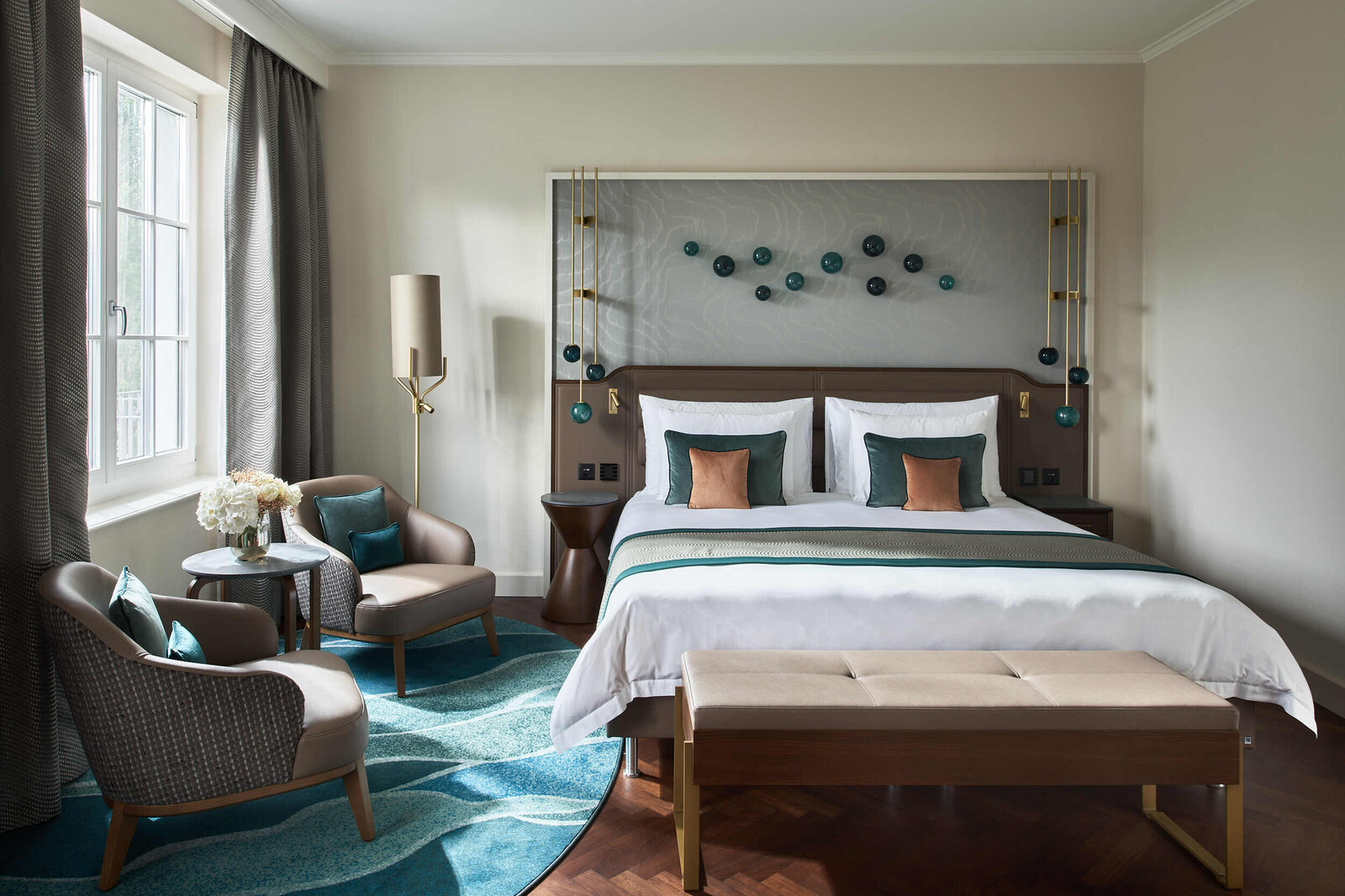 Frontal view of the bed as well as the sitting area of a Grand Deluxe room at the Grand Hotel Hof Ragaz.