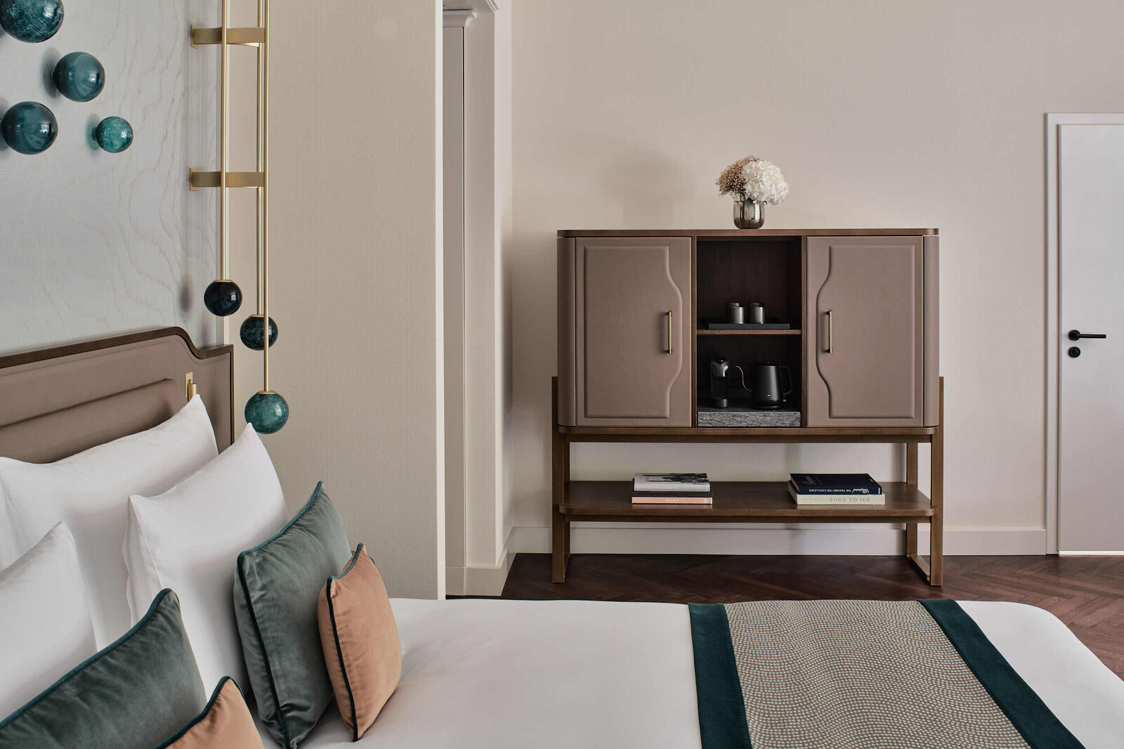 Looking over the bed towards a chicly decorated dresser with two doors and a recess in the middle.