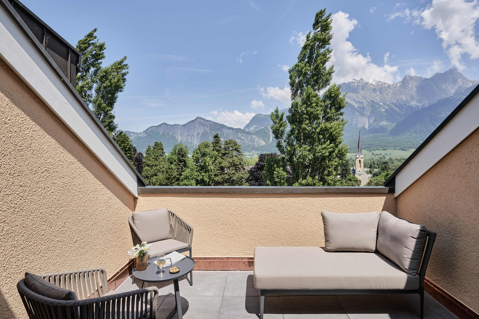 View of the balcony of a Two Bedroom Suite at the Grand Hotel Hof Ragaz. In the background is a breathtaking mountain scenery.
