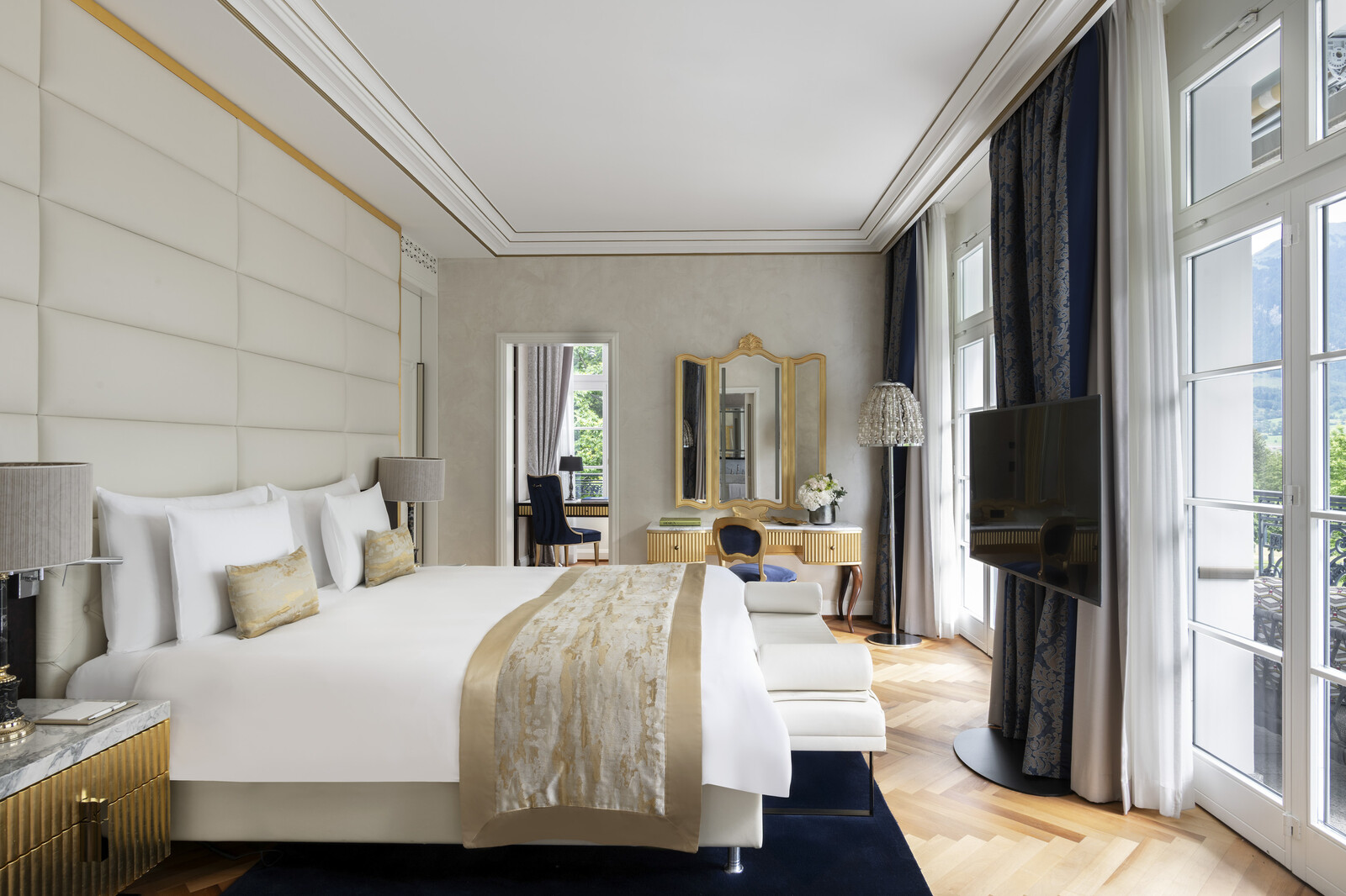 Elegant bedroom with make-up mirror and large television in the King Suite in the Grand Resort Bad Ragaz