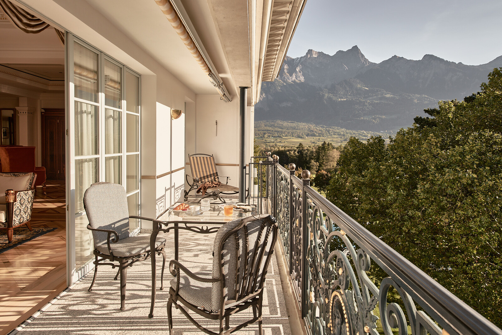 Elegant balcony with wrought iron furniture overlooking a scenic mountain view.