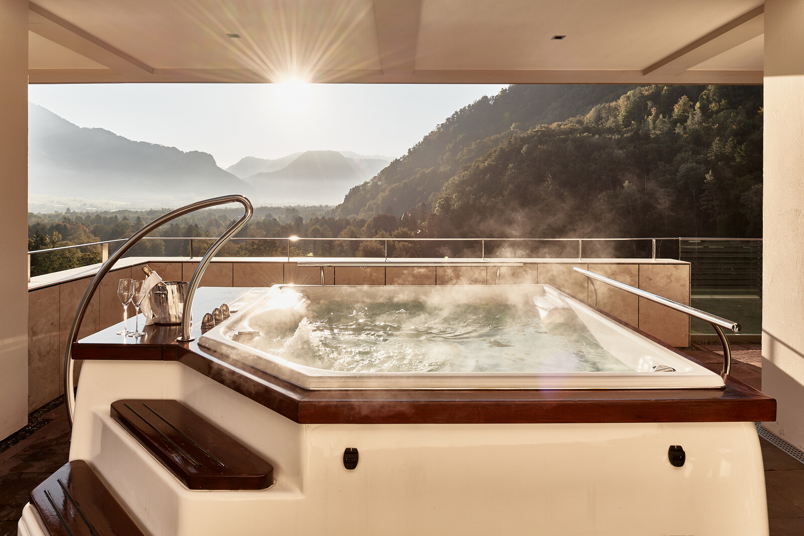Whirlpool auf dem Dach mit aufsteigendem Dampf und Blick auf die nebligen Berge bei Sonnenaufgang.