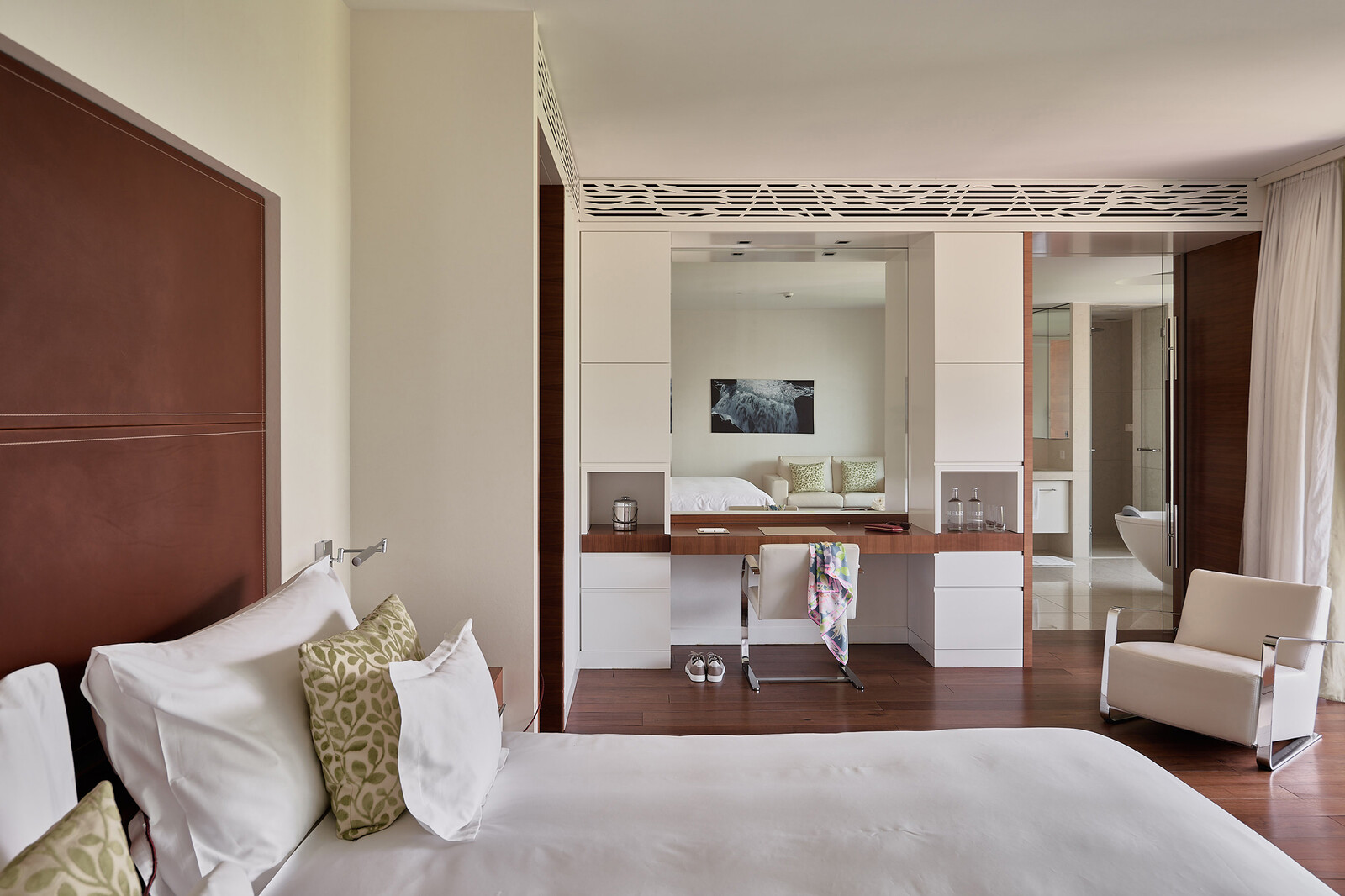 Ein Schlafzimmer in hellen Farben mit einem grossen Bett, einem Sessel und einem Schreibtisch und Stuhl im Spatower des Grand Resorts Bad Ragaz.