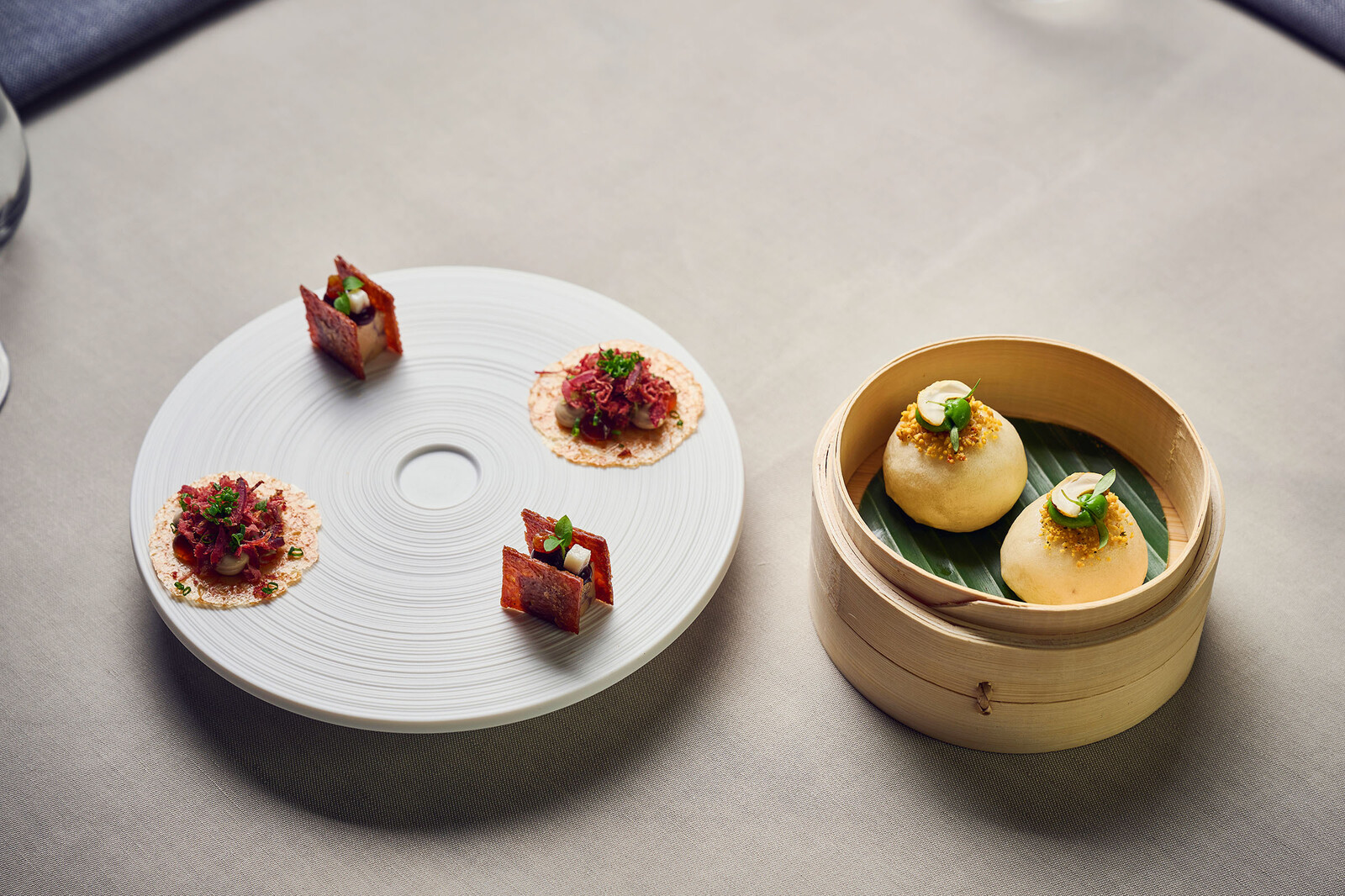 Eine Portion Ente von Widder, angerichtet auf einem Weissen Teller und in einer kleinen Holzschale.