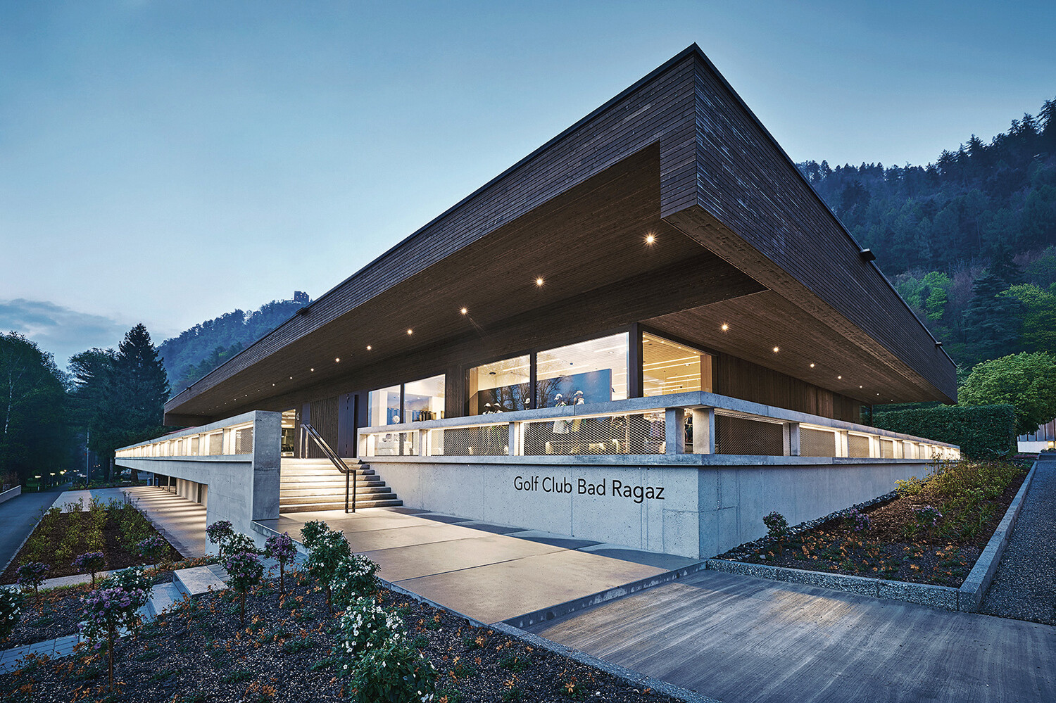 Das moderne Clubhaus des Golf Clubs Bad Ragaz von außen bei Abend.