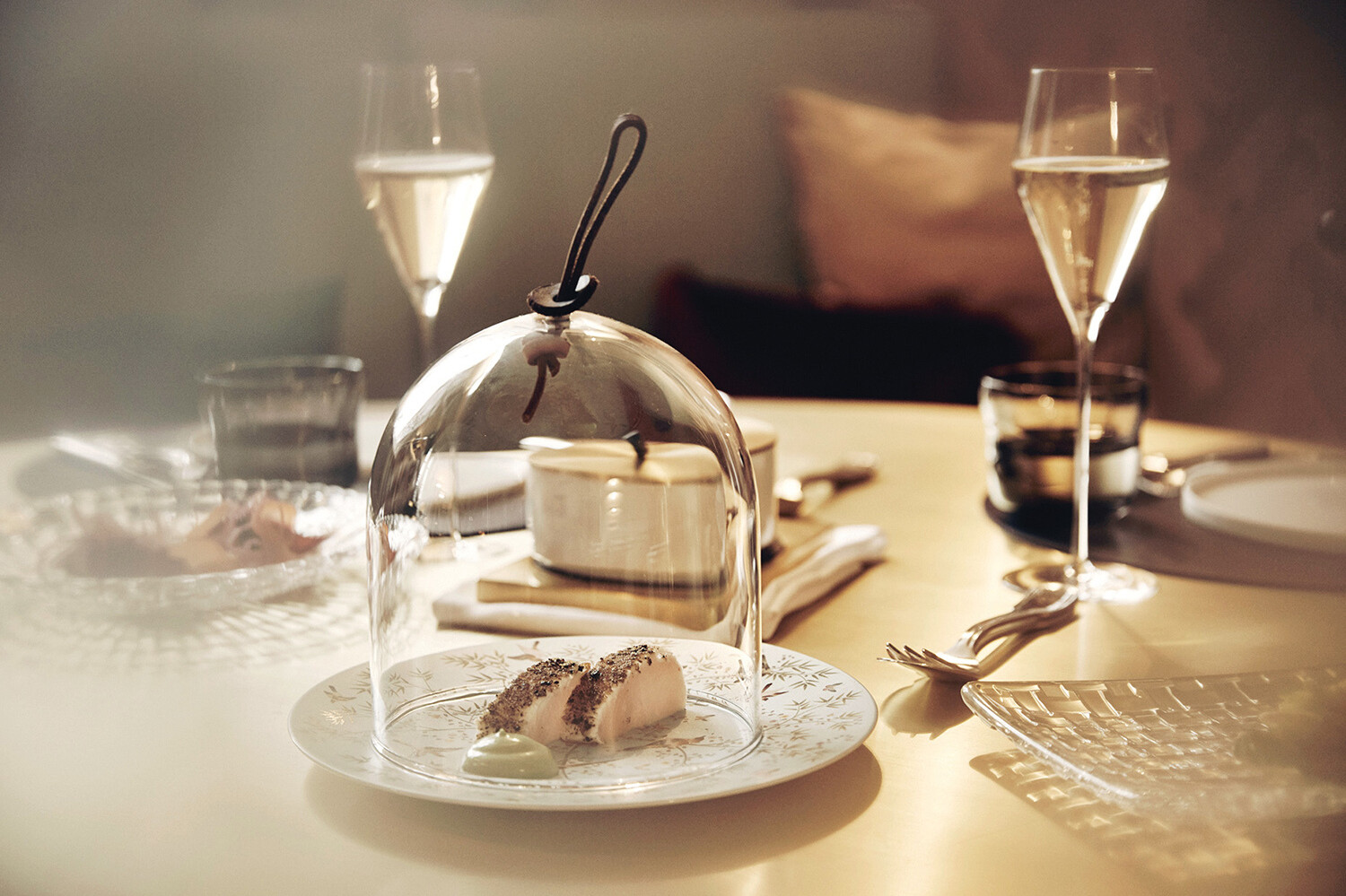 Ein Tisch gedeckt mit feinem Champagner und einem Dessert unter einer Glasglocke