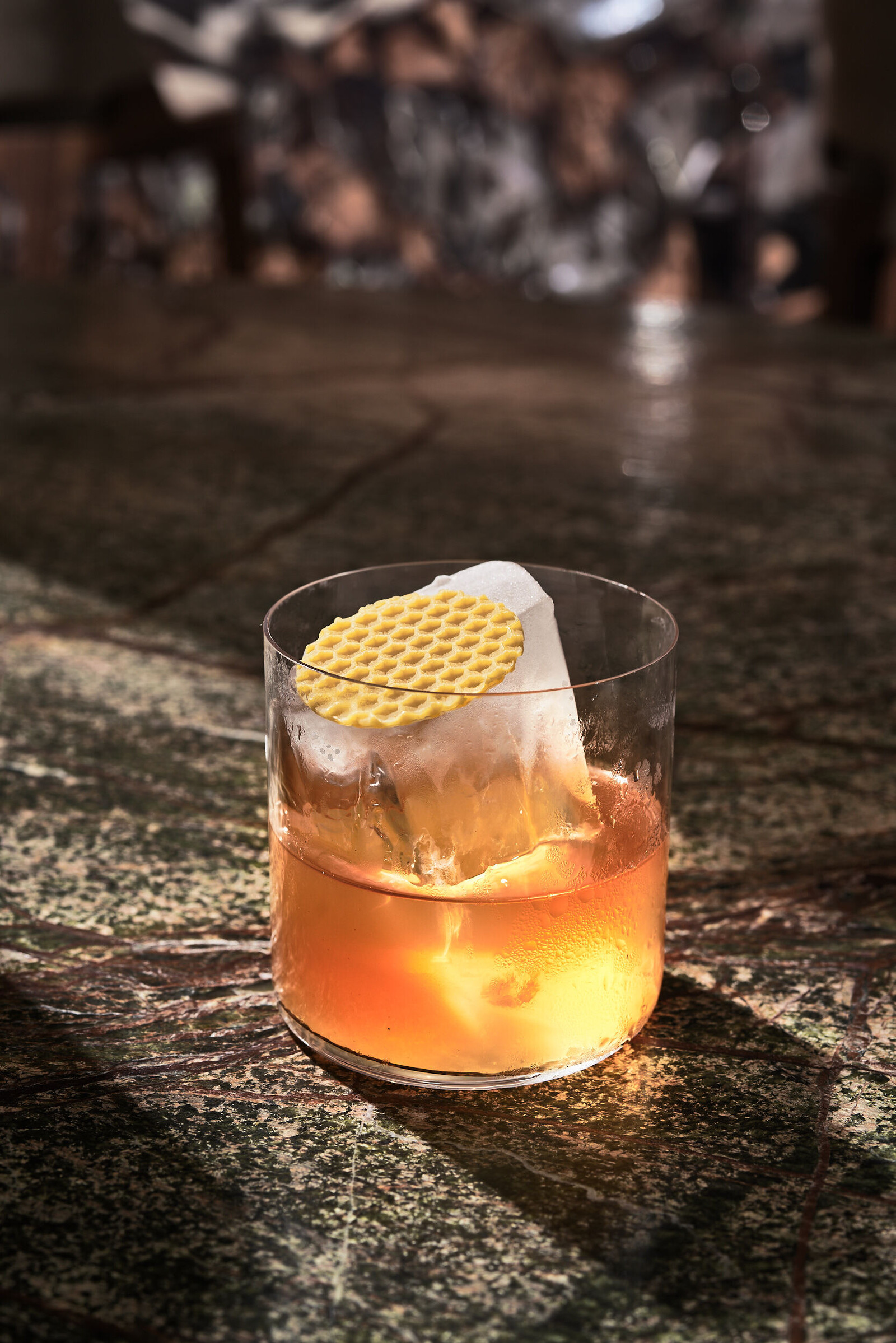 Ein orangefarbener Drink serviert mit Eiswürfel und einer Waffel im Restaurant Verve.