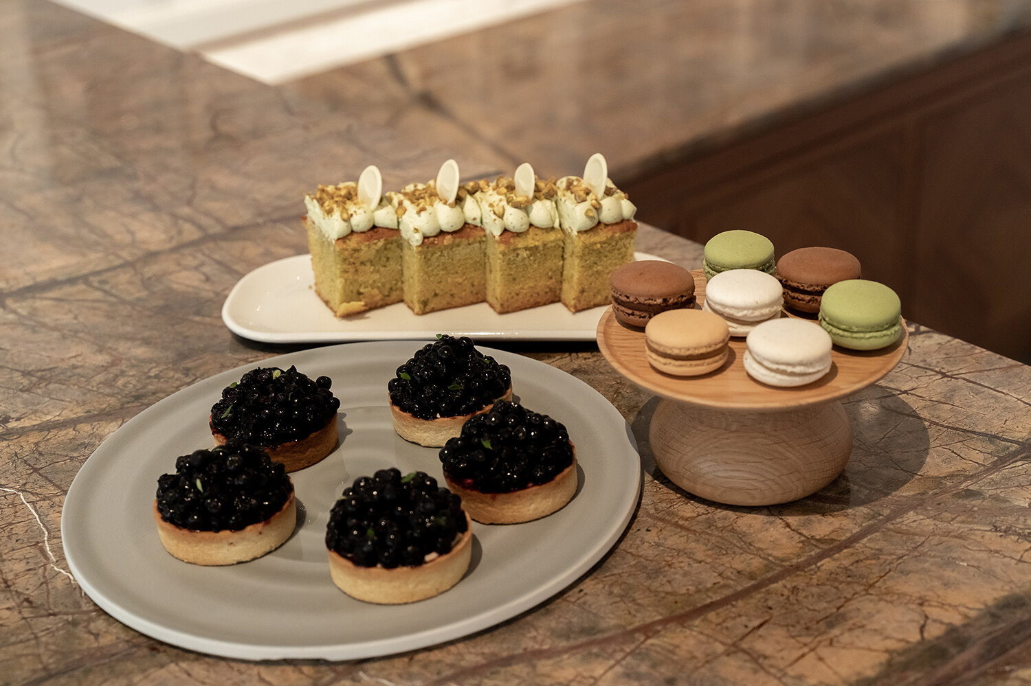 Verschiedene Süssgebäcke auf Tellern auf einem Holztisch.