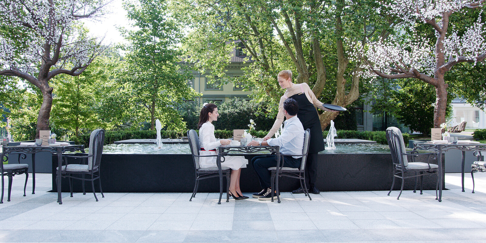 Eine Kellnerin serviert einem Paar auf der Terrasse des Restaurants Verve Kaffee.