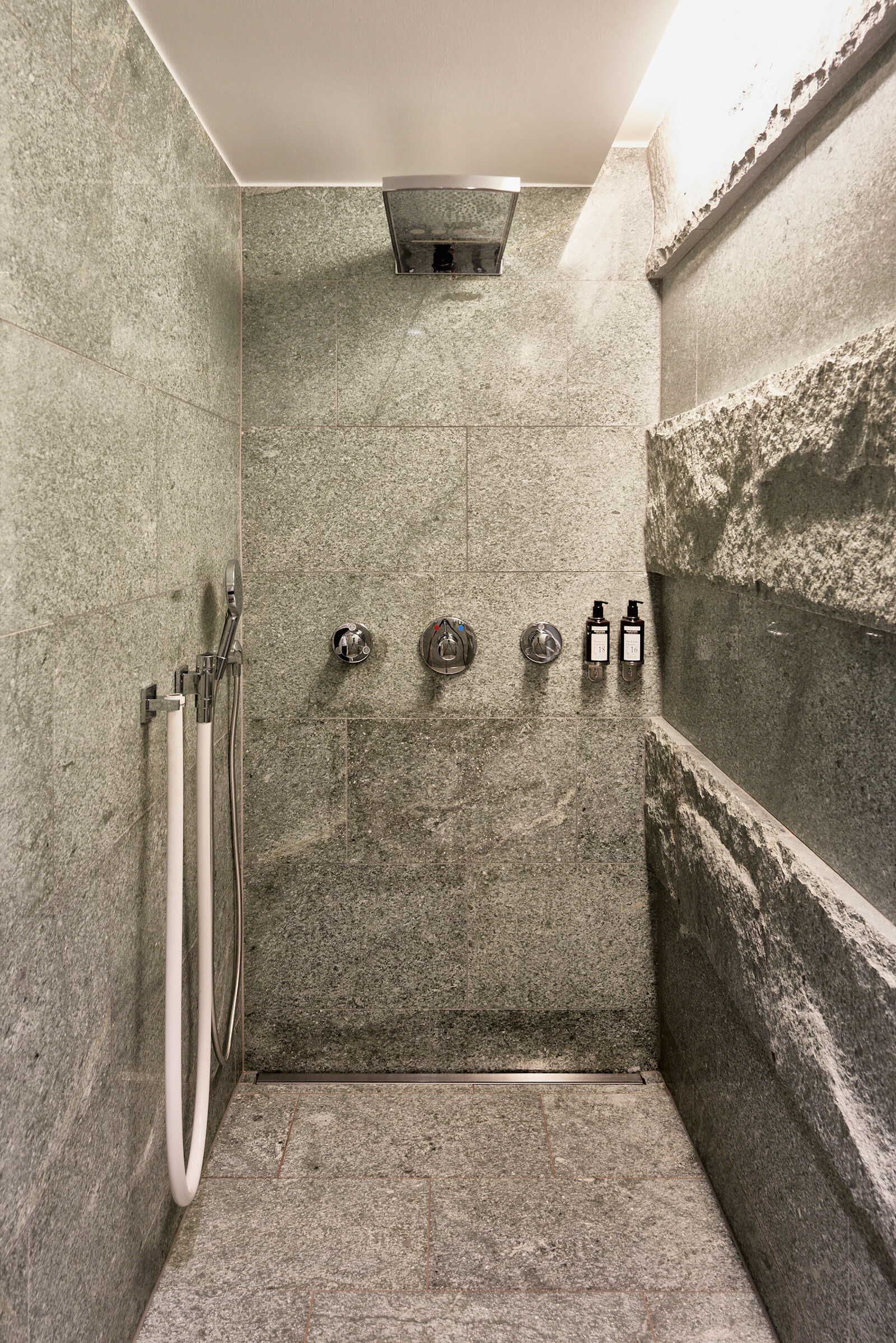 A free-standing natural stone shower in the private area of ​​the Thermal Spa at the Hotel Grand Resort Bad Ragaz, a superior luxury resort in Switzerland.