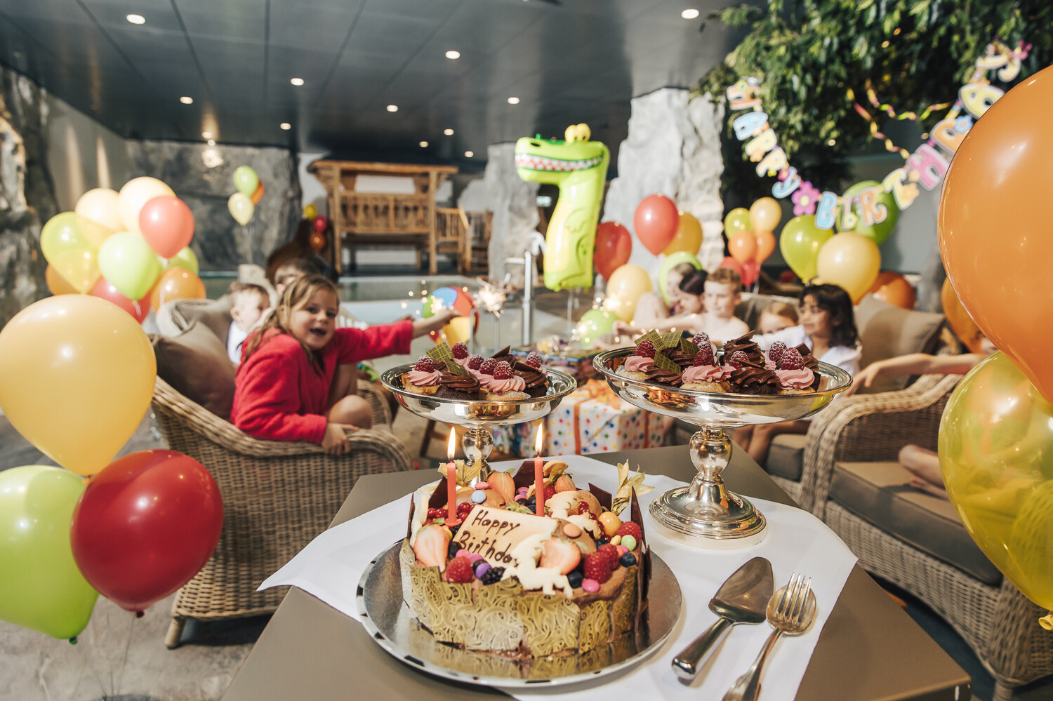 Children celebrate a child's birthday with cake and colored balloons in the Family Spa at the Grand Resort Bad Ragaz.