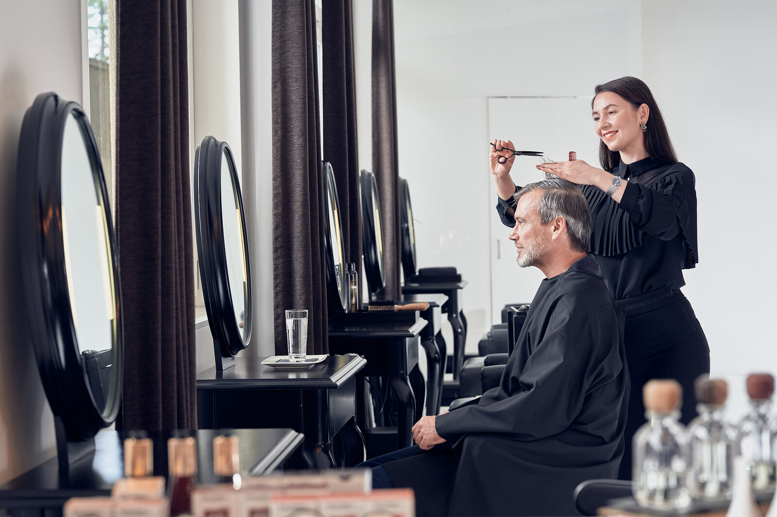 A hairdresser is cutting a man's hair.