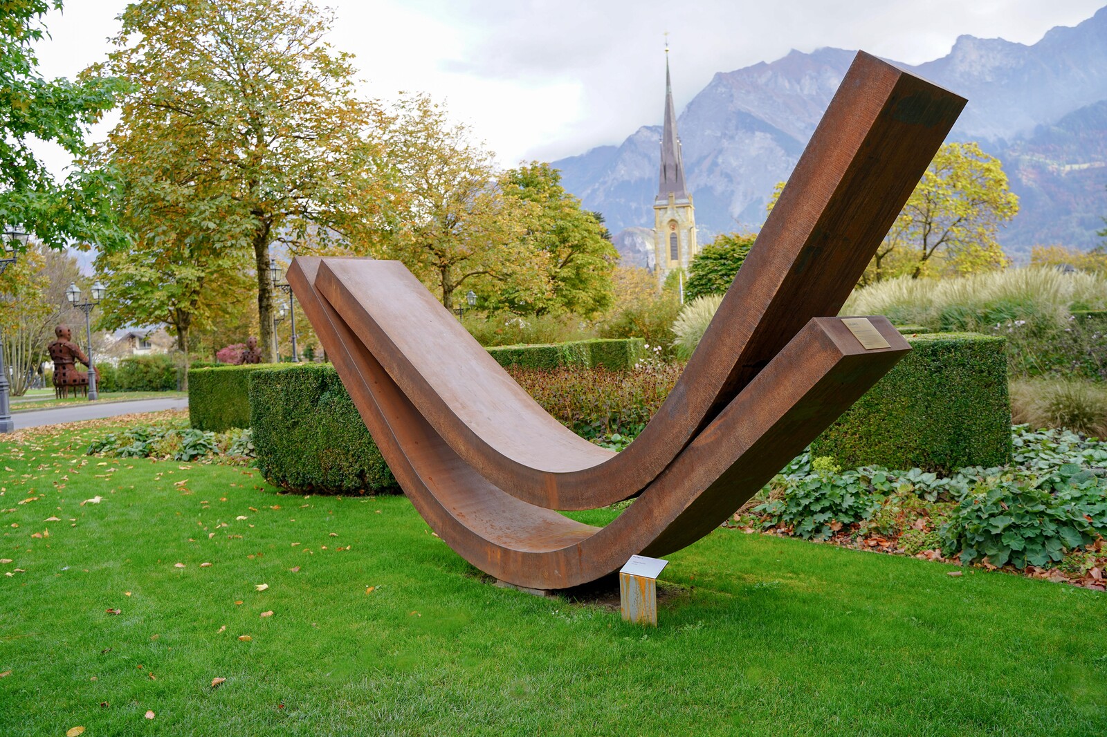 Balance von Thoms Röthel: Dieses Werk befindet sich links neben dem Eingang des Grand Hotel Quellenhofs und zeigt zwei Elemente aus Stahl, die sich aneinanderschmiegen. Allein durch ihre Form und das Gewicht werden sie in einer labilen Stabilität gehalten.