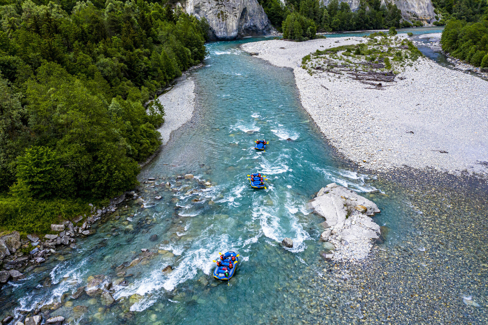 Eine Aufnahme des Vorderrheins von oben, während drei blaue Gummibote durch den Fluss schwimmen.