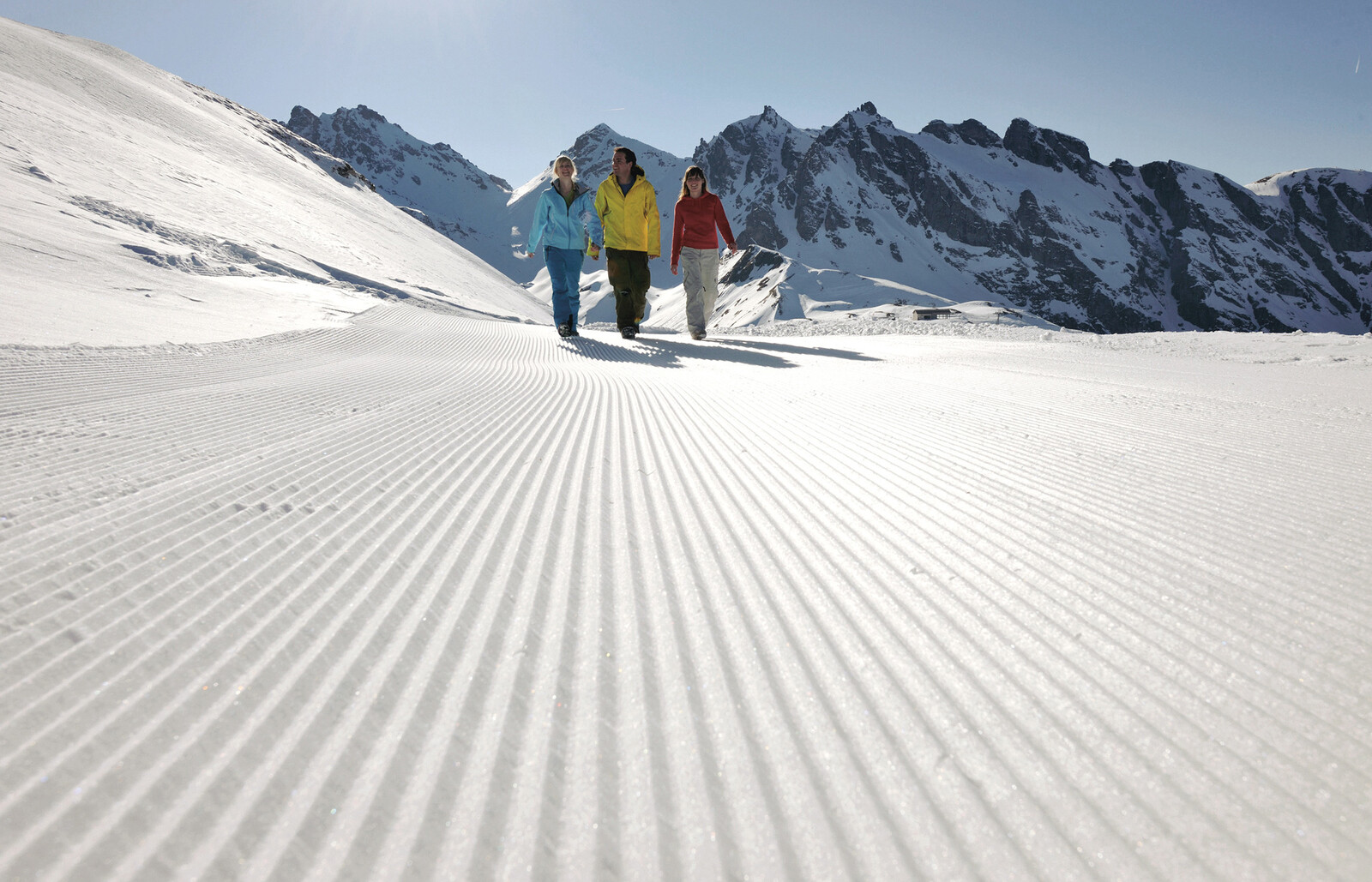 Drei Gäste machen einen Winterspaziergang durch die schneebedeckten Berge.