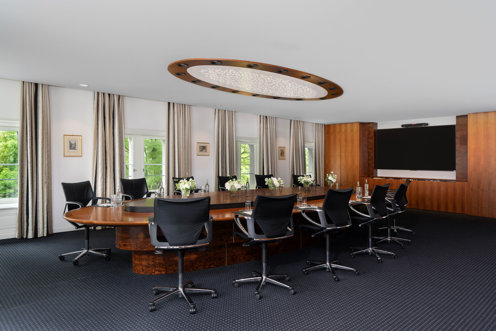 Im Kursaal ist der Board Room bereits für ein Meeting vorbereitet. Ein runder Holztisch befindet sich in der Mitte des Raumes. Stühle stehen um diesem herum. Über dem Tisch hängt ein grosser Kronleuchter. Die Fenster sind mit weissen Vorhängen verdeckt. Der Kursaal gehört zum Hotel Grand Resort Bad Ragaz, einem Superior Luxushotel in der Schweiz.