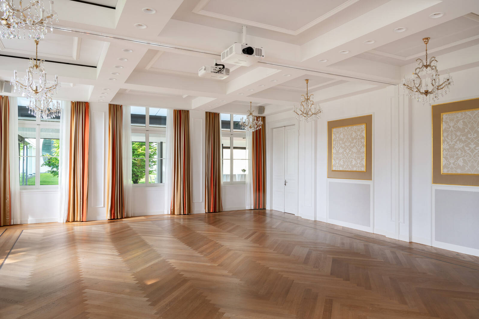 Der Rainer Maria Rilke Saal steht leer. Die Vorhänge an den Fenstern sind Golden. Der Fussboden besteht aus Holz. Der Kursaal gehört zum Hotel Grand Resort Bad Ragaz, einem Superior Luxushotel in der Schweiz.