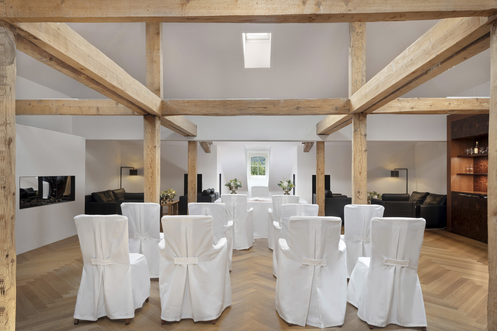 Die Victor Hugo Lounge des Grand Hotel Bad Ragaz im festlichen Hochzeits-Setup mit weissen Stuhlhussen und floralen Tafelaufsätzen. Gemütliche Sitzbereiche und sanfte Beleuchtung schaffen eine warme, einladende Atmosphäre.
