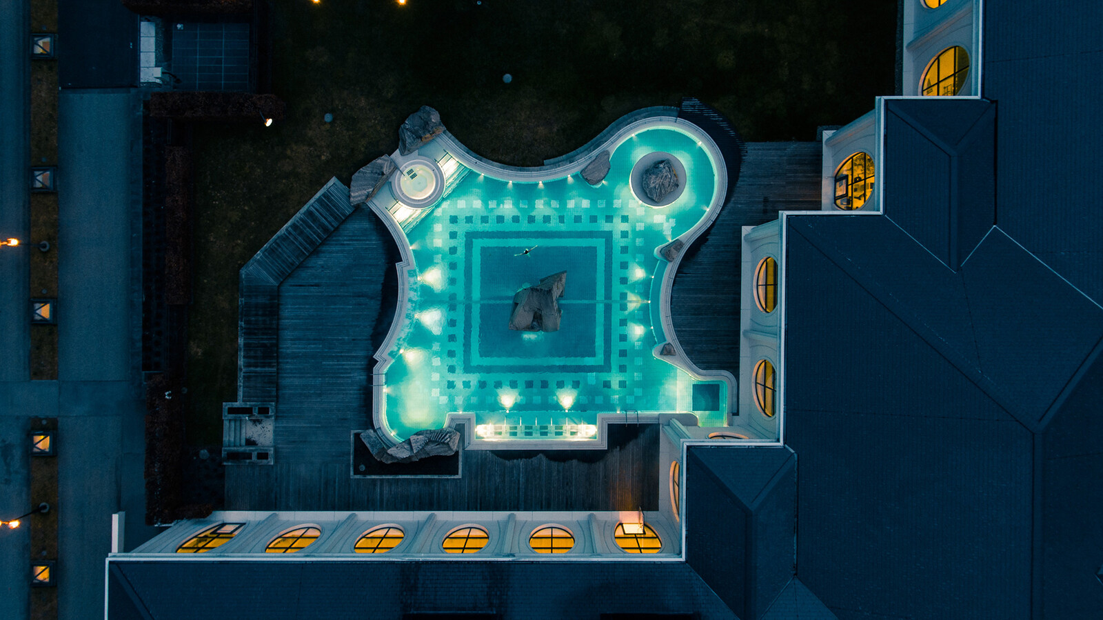 The evening atmosphere is noticeably noticeable in the outdoor area of ​​the Tamina Therme. The steam rises above the pool. The mountains can be seen behind the Tamina Therme. The bathroom is attached to the wellness hotel Grand Resort Bad Ragaz, a superior luxury hotel in Switzerland.