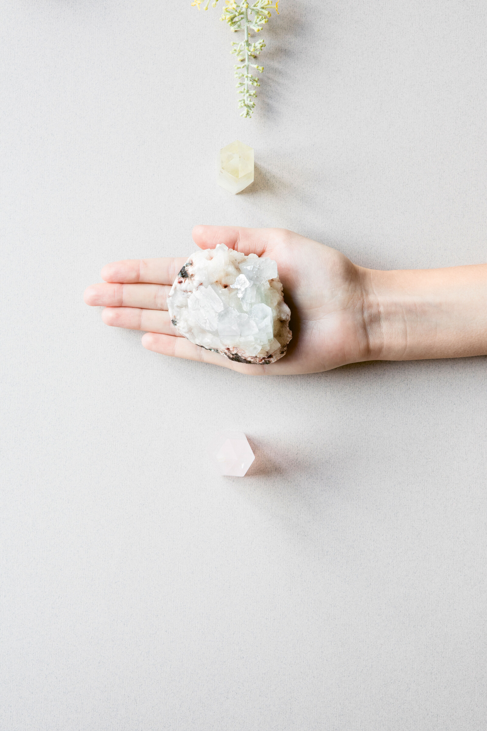 Eine Hand hält einen grossen weissen Kristall in der Hand. Um ihre Hand herum liegen noch mehr kleinere Kristalle. Das Wellnessresort Grand Resort Bad Ragaz ist ein Luxushotel in der Schweiz.