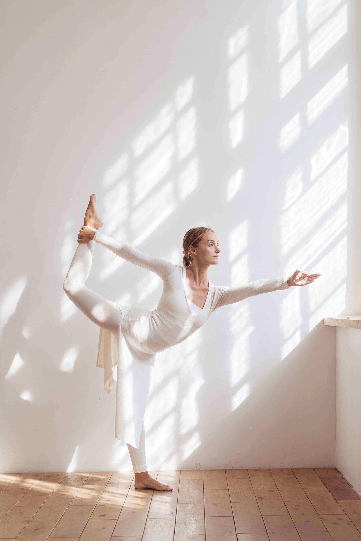 Eine Frau in gemütlicher Kleidung führt eine Yoga-Position in ihrer Wohnung aus.