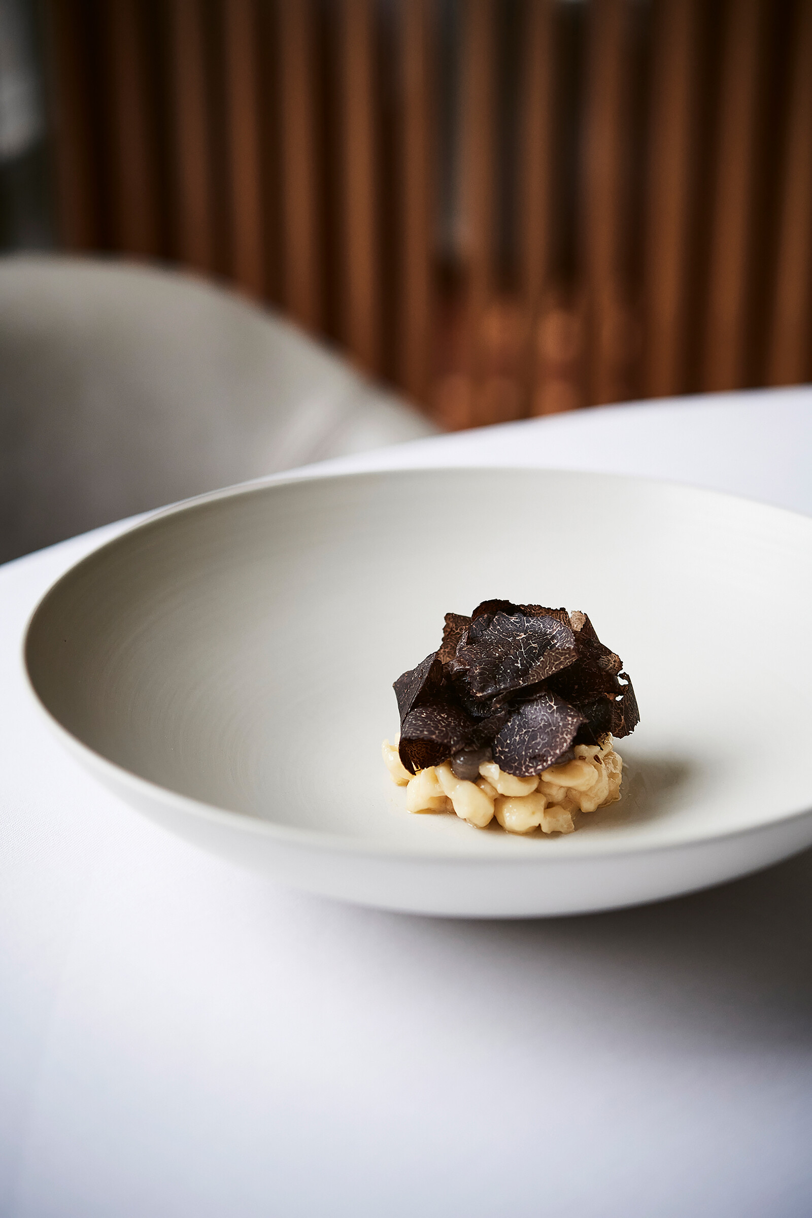 Blick auf auf einen minimalistischen Teller im Restaurant Memories. Im Teller befindet sich eine sauber angerichtete Portion Knöpfle mit Trüffeln.