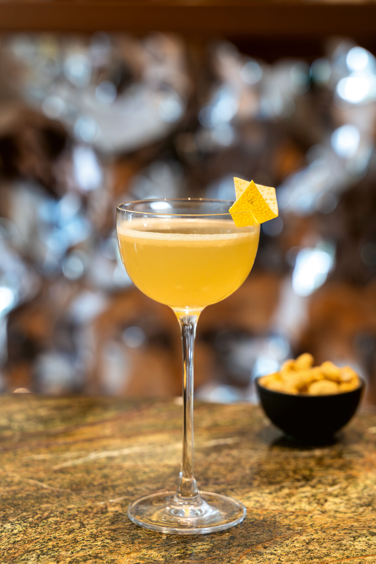 Blick auf den Bees & Knees des verve by sven. Der alkoholfreie Drink ist gelb und wurde in einer Cocktailschale mit einer Zitronenzeste angerichtet.