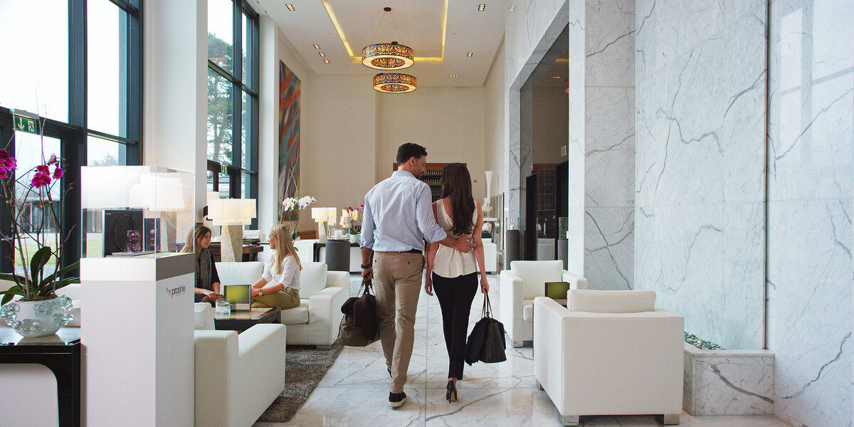 Paar läuft mit Handgepäck durch den stilvollen Eingangsbereich des Hotels